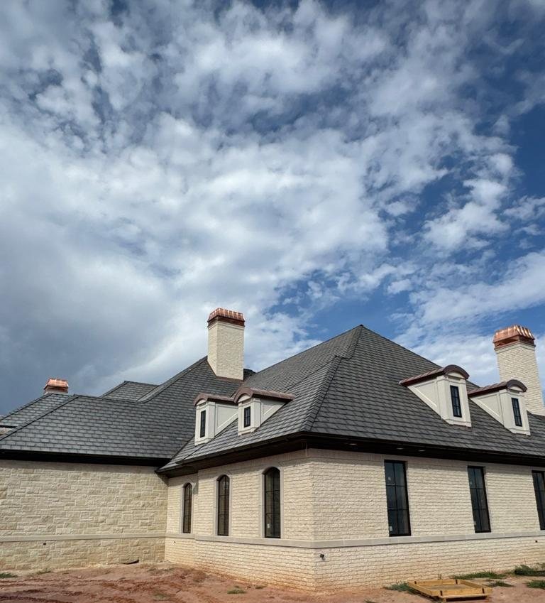 Finished slate style roof with dormers and tall brick chimneys on a new Oklahoma City home