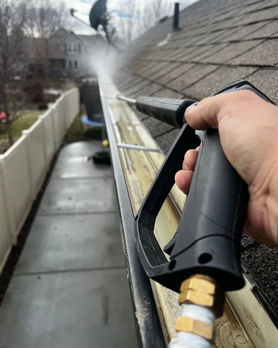 A gutter being cleared with a pressure washer, seen from the roof edge