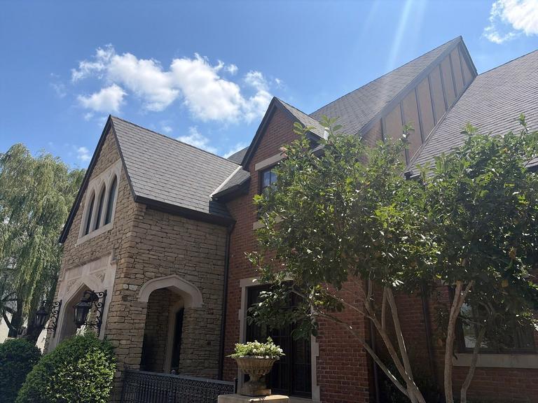 Tudor-style stone and brick estate with slate-look shingle roof in Norman, Oklahoma